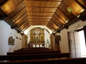 Nave interior con bancos y retablo al fondo en la iglesia de Carbajosa, La Sobarriba (León)